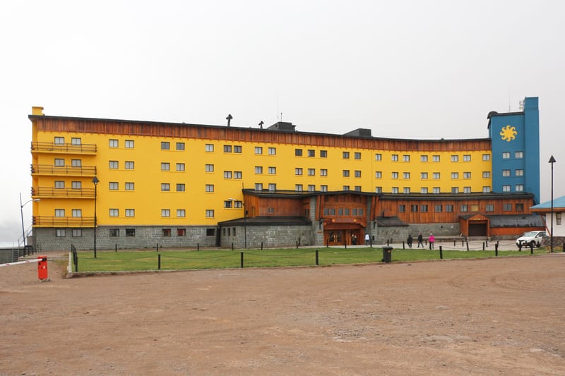 The yellow Portillo hotel below snowy slopes, beside the international route.